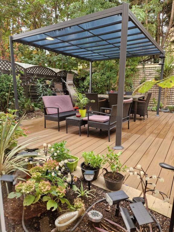 une terrasse avec un auvent bleu, des chaises et des plantes dans l'établissement Jasmin, à Vitry-sur-Seine