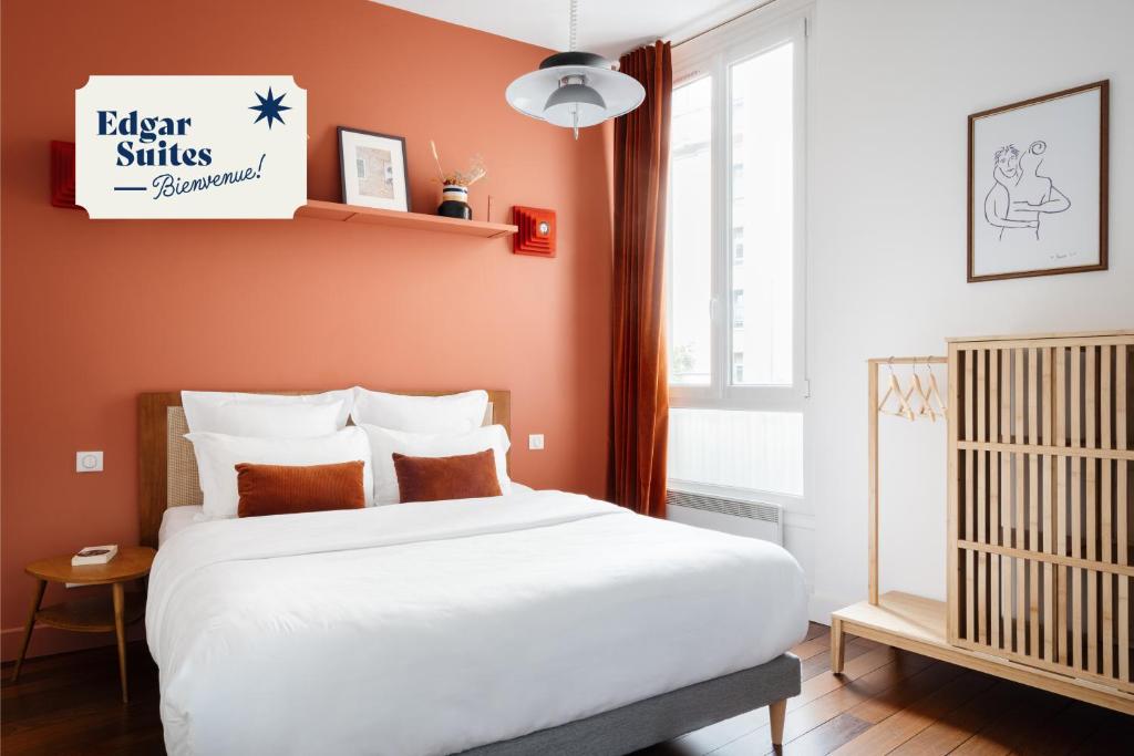 um quarto com uma cama branca e uma parede laranja em Edgar Suites Louvre - Saint-Honoré em Paris