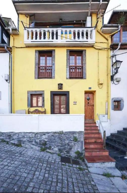 a yellow house with a staircase in front of it at La Casina de la Peña in Luarca