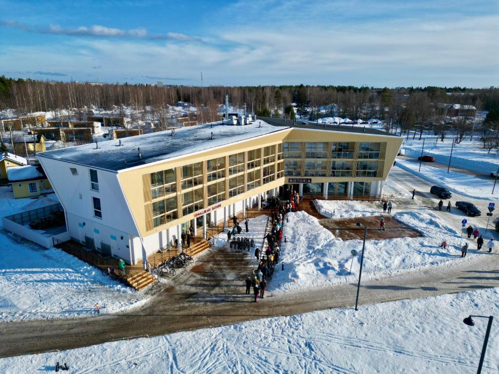 budynek w śniegu z ludźmi stojącymi przed nim w obiekcie Nallikari Holiday Village - Aalto Seaside Apartments w mieście Oulu