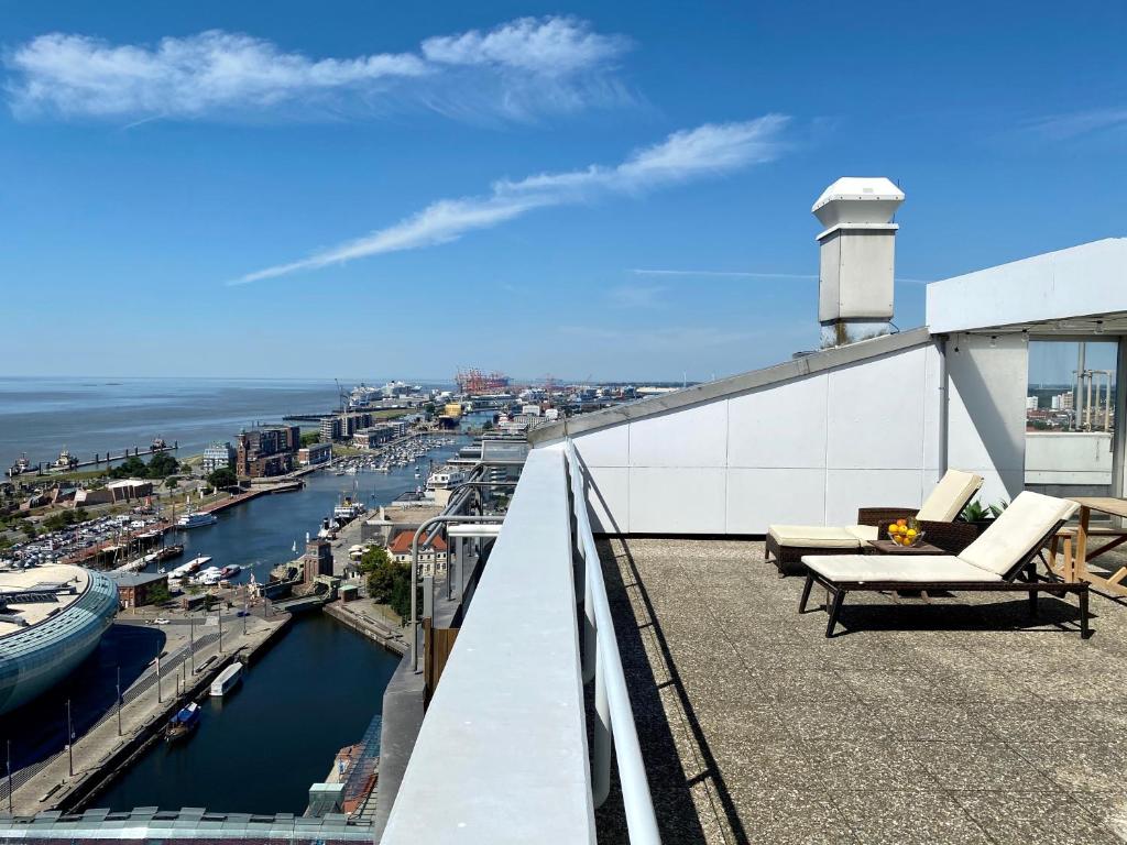 einen Balkon mit Stühlen und Hafenblick in der Unterkunft COAST HOUSE Sky Suite in Bremerhaven