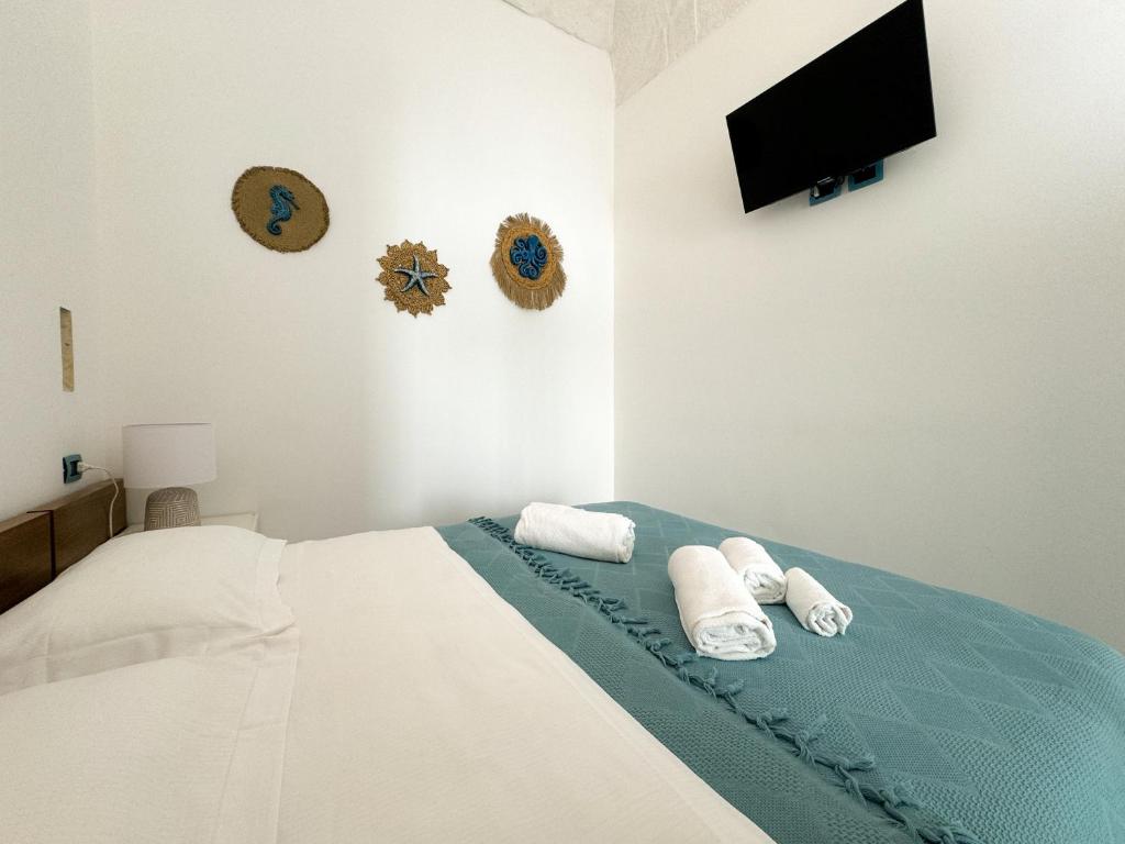 a bedroom with a bed with towels and a flat screen tv at Vingt Sept in Polignano a Mare