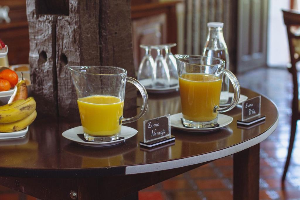 two glasses of orange juice on plates on a table at Hotel Palacio La Casona de Cerrazo in Cerrazo