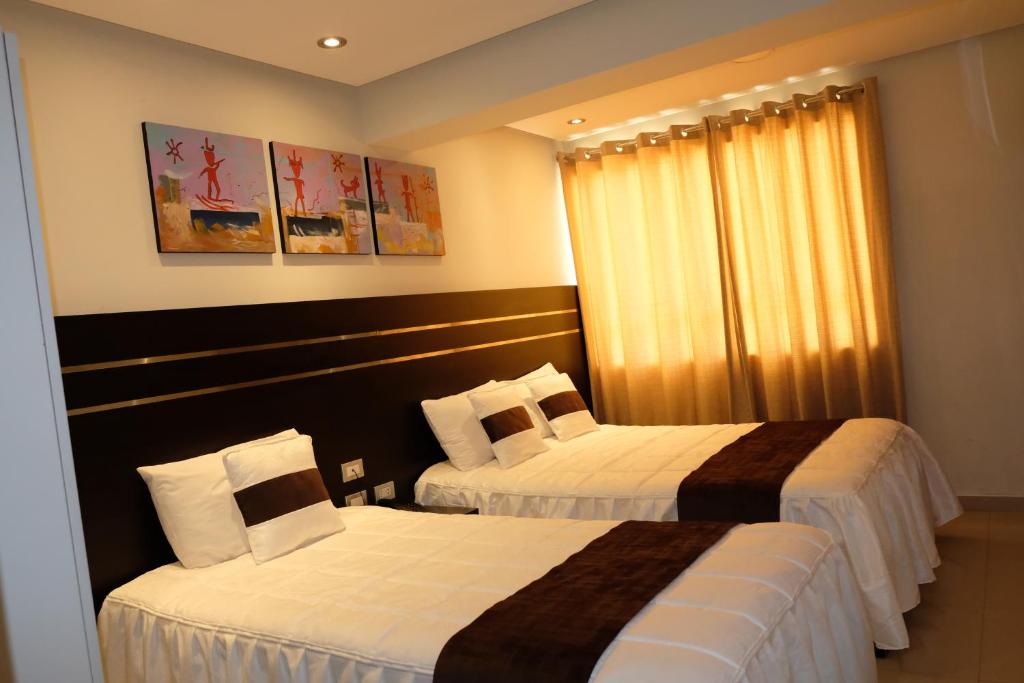 a hotel room with two beds and a window at Hotel Puma'r Tacna in Tacna