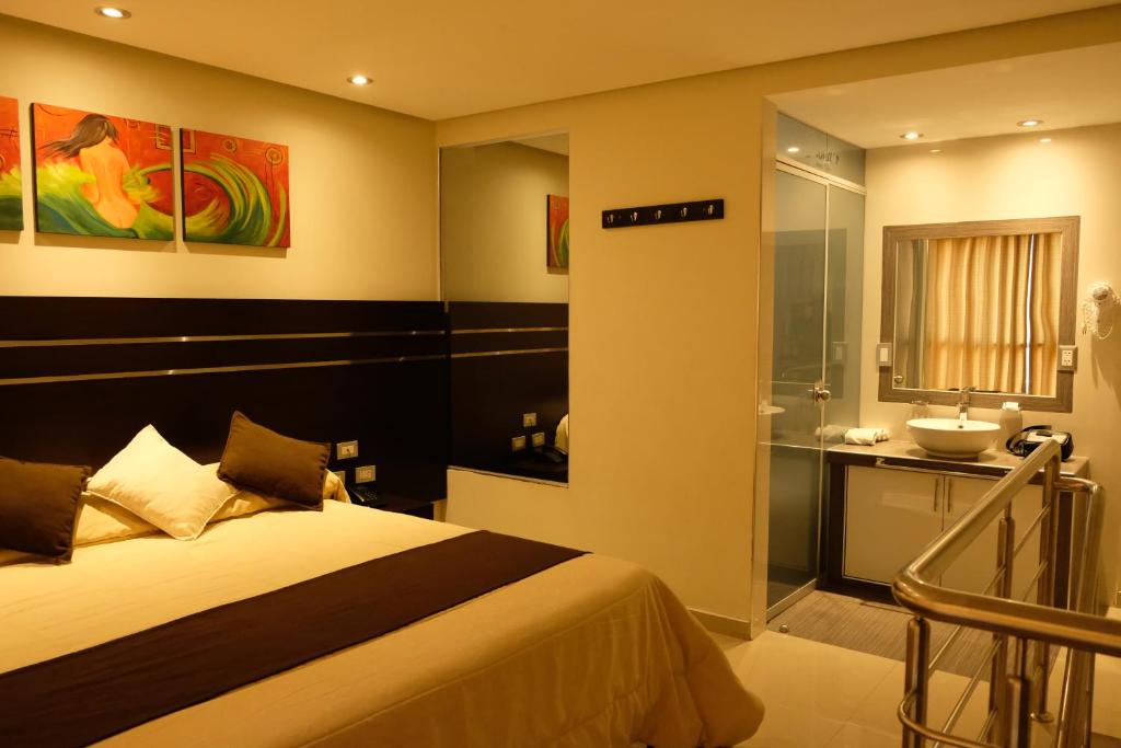 a bedroom with a bed and a bathroom with a sink at Hotel Puma'r Tacna in Tacna
