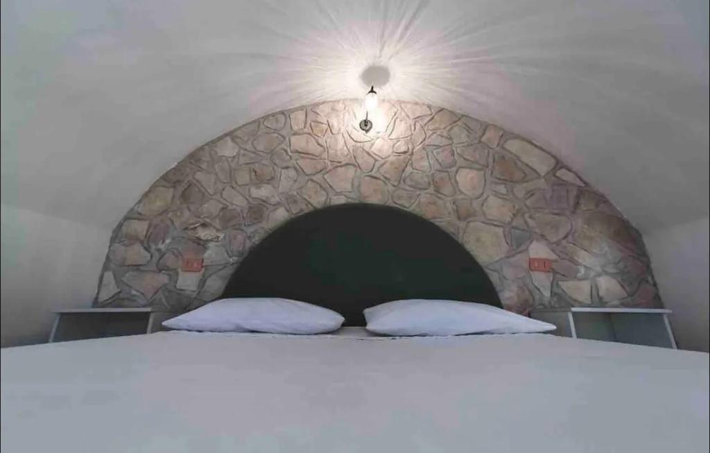 una camera da letto con un muro in pietra e un letto con due cuscini di Casetta direttamente sul mare a Peschici