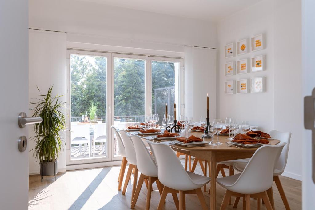 een eetkamer met een tafel en witte stoelen bij Pins Dorés - A Luxurious and beautifully decorated villa with terrace and parking near the beach in Knokke-Heist
