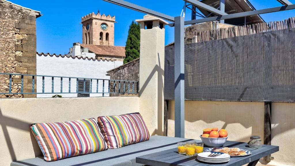 a table with a bowl of fruit on a balcony with a clock tower at Can Williams in Pollença