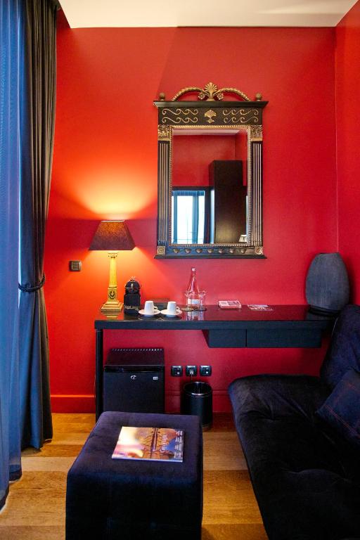 a red living room with a mirror and a couch at Farol Hotel in Cascais