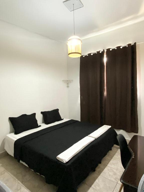 a bedroom with a black and white bed and a window at Quarto de Solteiro Uberaba in Uberaba
