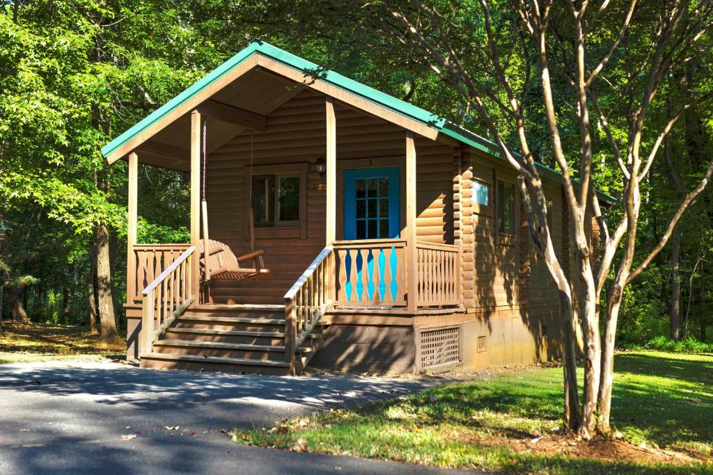 a small cabin with a porch and stairs to it at Carowinds Camp Wilderness in Charlotte