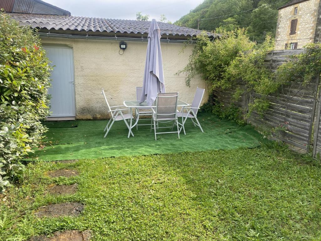 un patio avec une table, des chaises et un parasol dans l'établissement Loft et Appartement à la campagne, à Saint-Cyprien