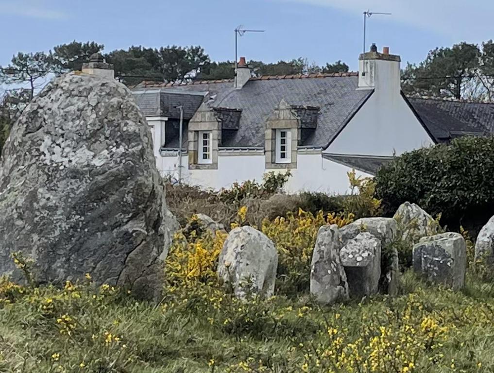 een grote rots voor een wit huis bij Maison vue sur les alignements de Carnac - Les Glycines in Carnac