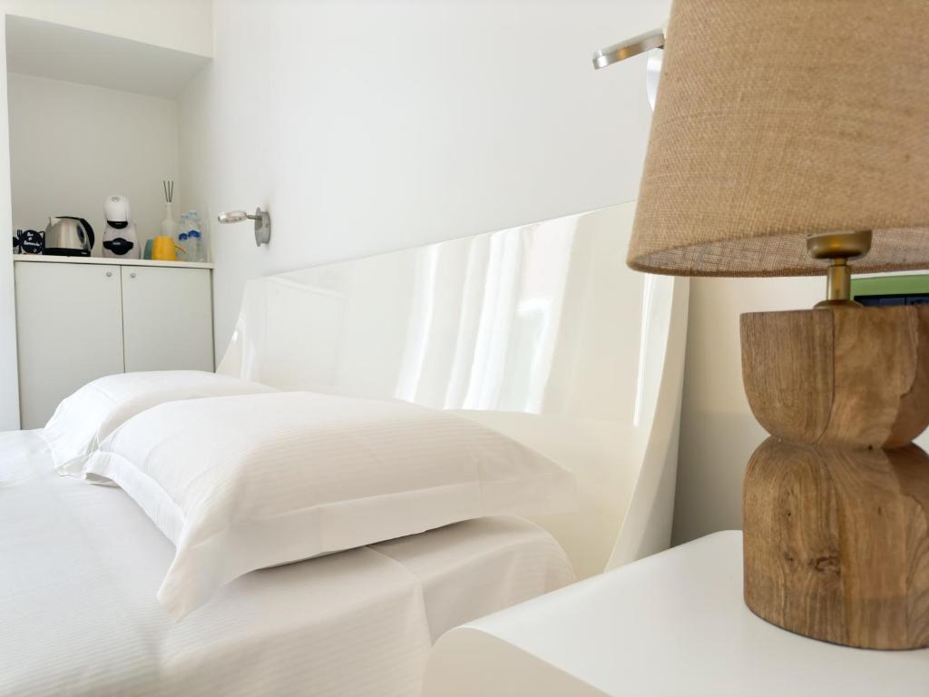 a white bedroom with a bed and a lamp at Vingt Sept in Polignano a Mare