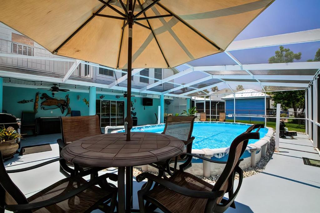 a table with an umbrella next to a swimming pool at *NEW* POOL screened-in, Waterfront, 4 Kayaks, Pet in Hernando Beach