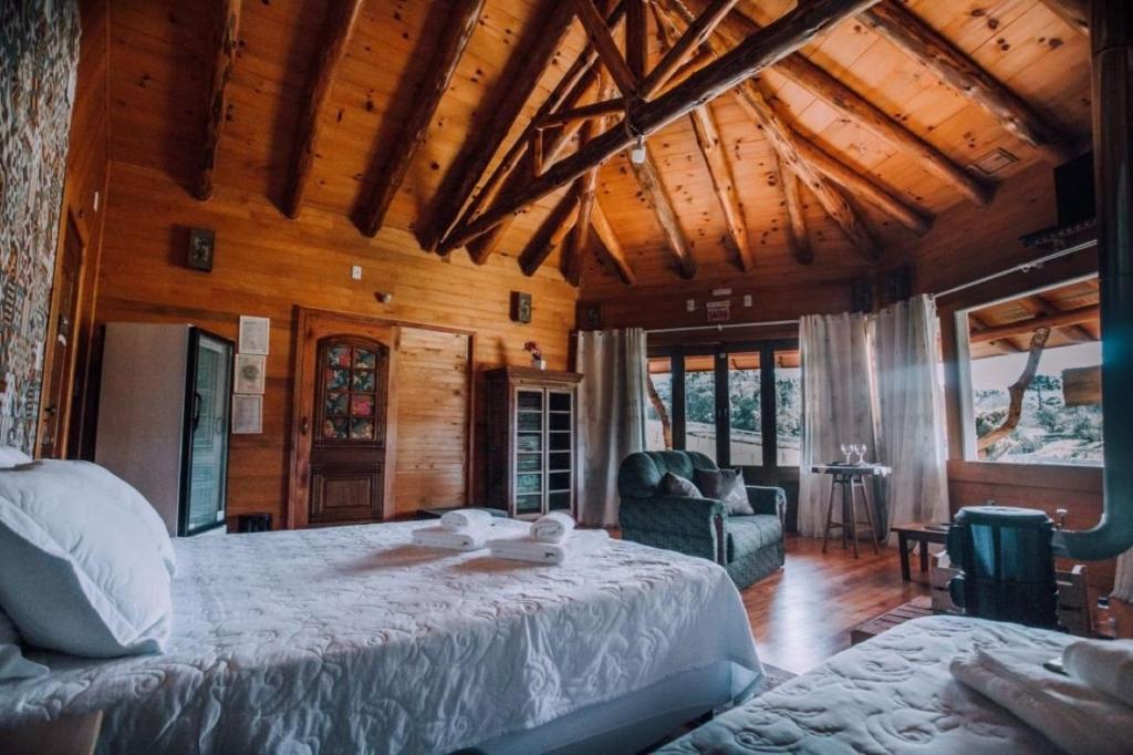 Un dormitorio con una cama grande en una habitación con techos de madera. en Pousada Caminhos do Mel - Urubici - SC, en Urubici