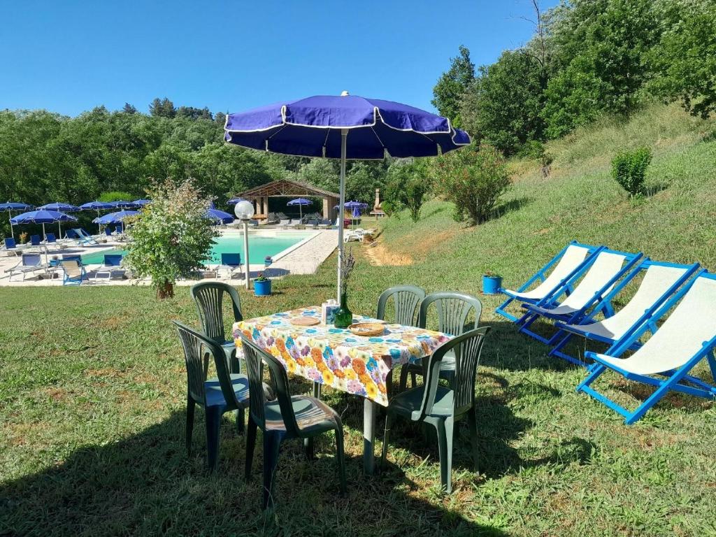einen Tisch mit einem Sonnenschirm und Stühlen sowie einen Pool in der Unterkunft Studio für 3 Personen ca 60 qm in Fauglia, Toskana Etruskische Küste in Fauglia