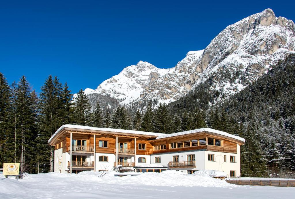 una casa nella neve con montagne sullo sfondo di Residence Reisenschuh a Vipiteno