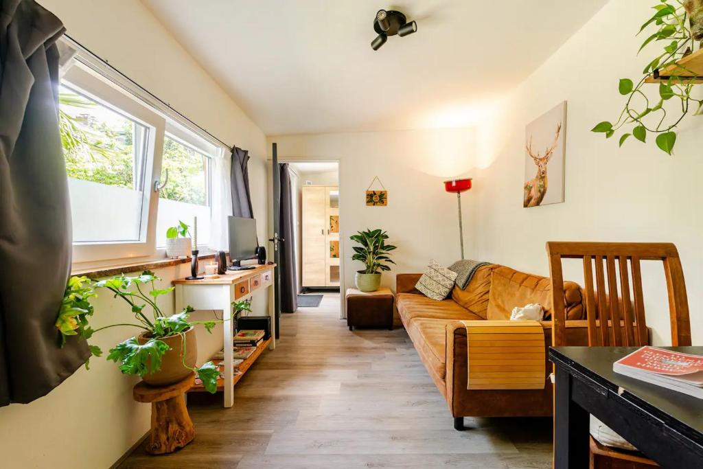 een woonkamer met een bank en een tafel bij Tiny house - fietsverhuur, eigen keuken en badkamer in Nijmegen
