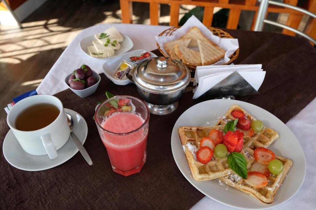 a table with a plate of waffles and a cup of coffee at Hotel Puma'r Tacna in Tacna