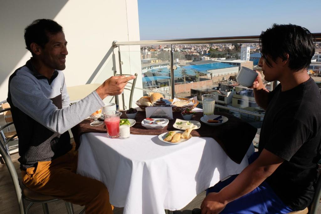 a couple of men sitting at a table with food at Hotel Puma'r Tacna in Tacna