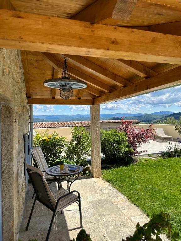 un patio avec une table et des chaises sous un toit en bois dans l'établissement Rural Apartments Ritossa, à Vižinada