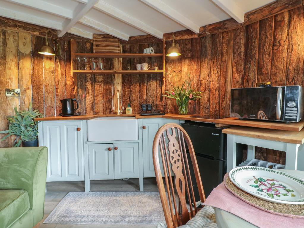 a kitchen with wooden walls and a counter with a microwave at The Lazy Squire by The Water in Rugeley