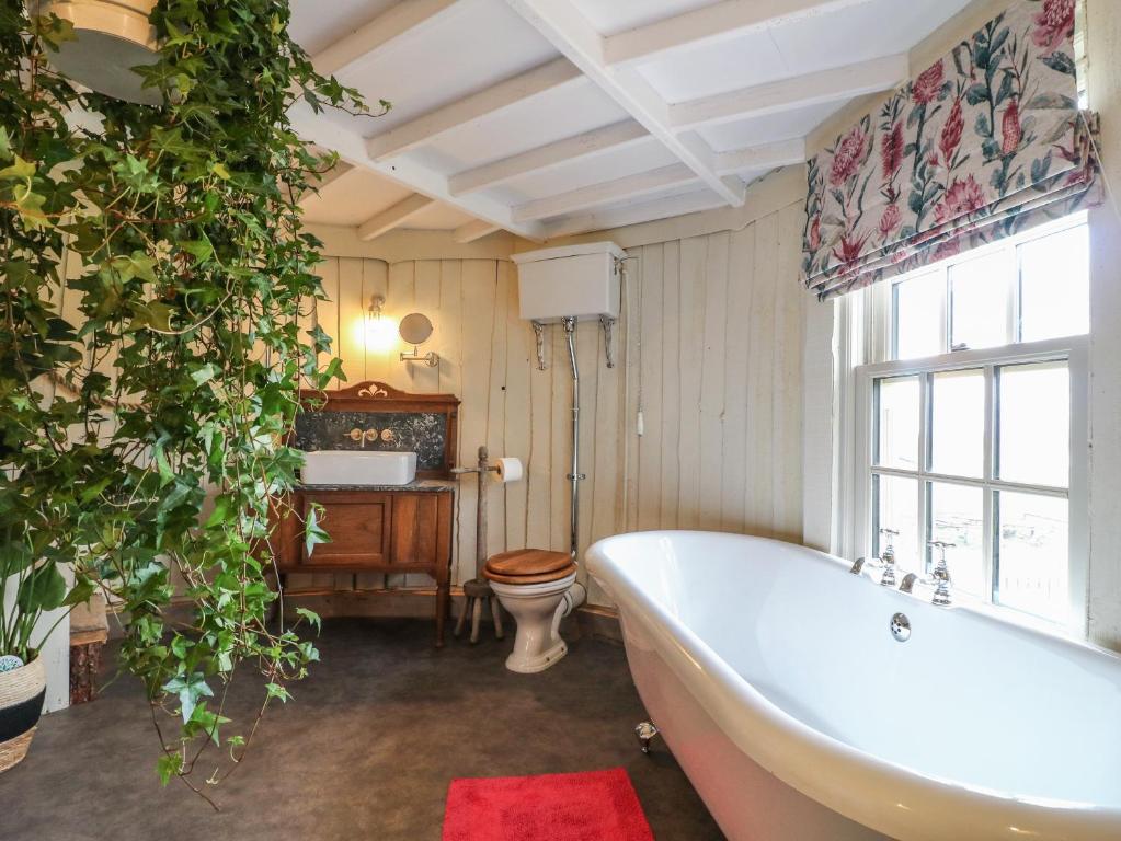 a bathroom with a tub and a toilet and a window at The Lazy Squire by The Water in Rugeley