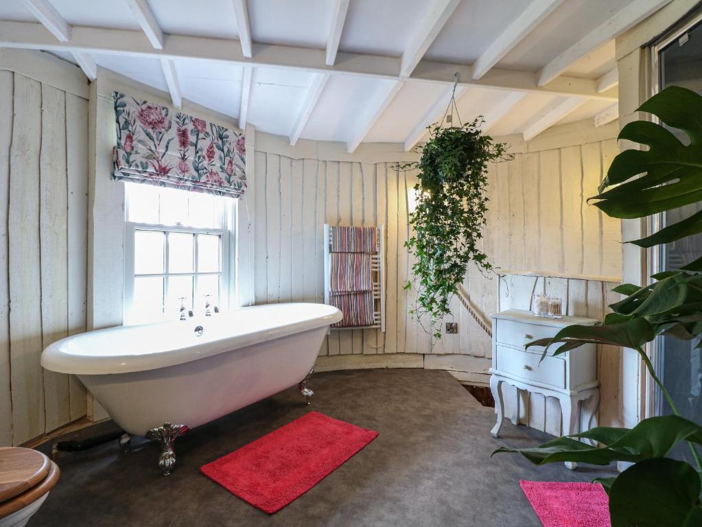a bathroom with a white bath tub and a window at The Lazy Squire by The Water in Rugeley