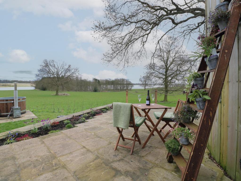 a table and chairs on a patio with a view of a field at The Lazy Squire by The Water in Rugeley