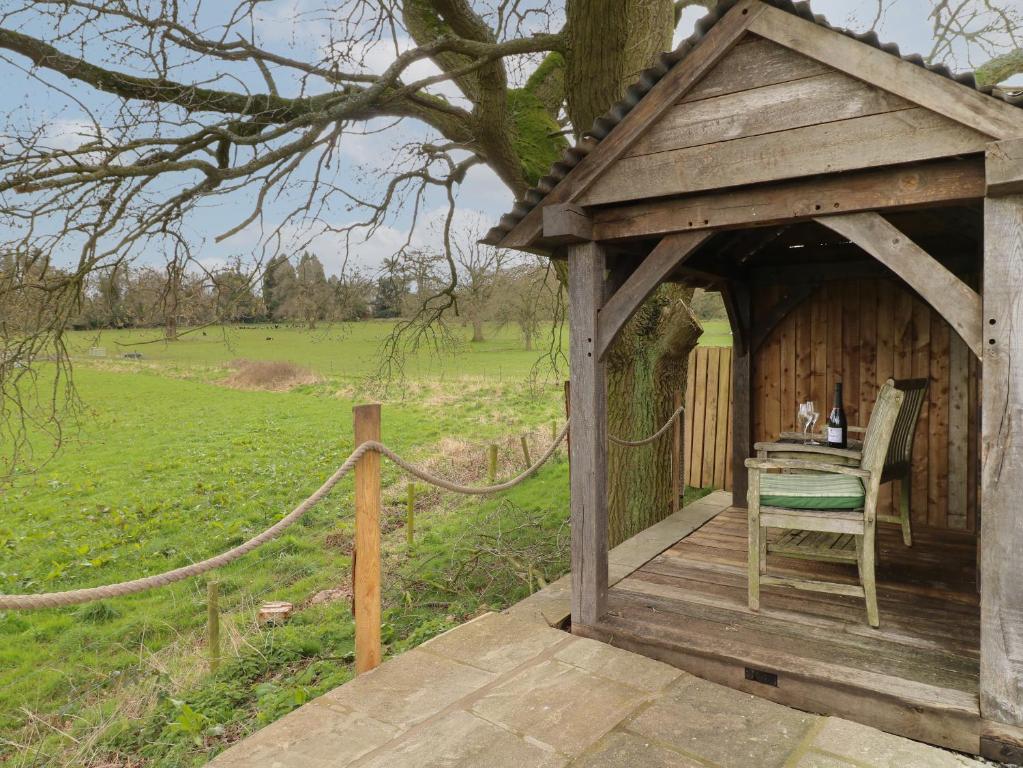 a wooden gazebo with a table and a chair at The Lazy Squire by The Water in Rugeley