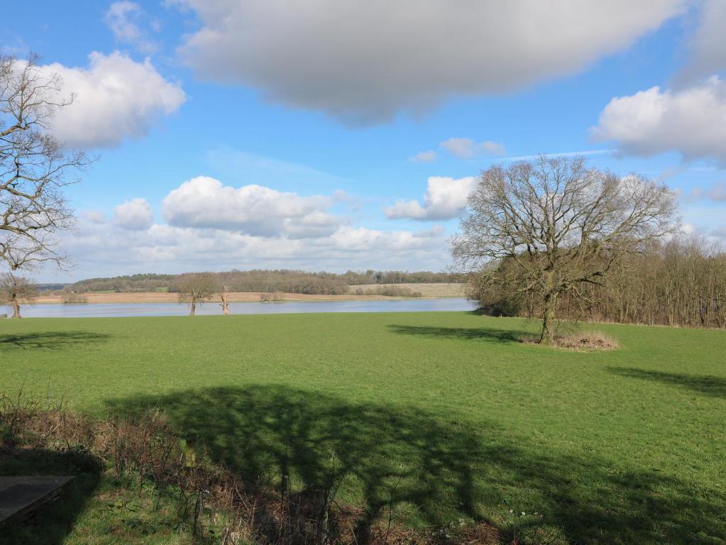 a large green field with a large body of water at The Lazy Squire by The Water in Rugeley