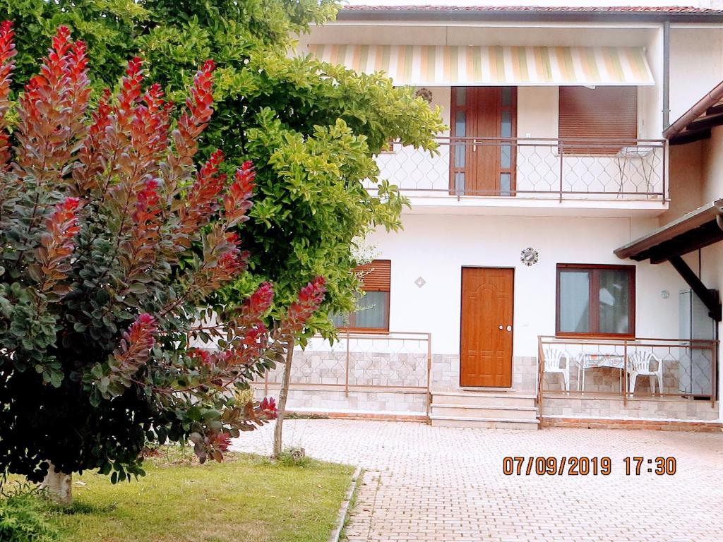 dom z czerwonymi kwiatami przed drzewem w obiekcie 5 Palme w mieście Terzo dʼ Aquiléia