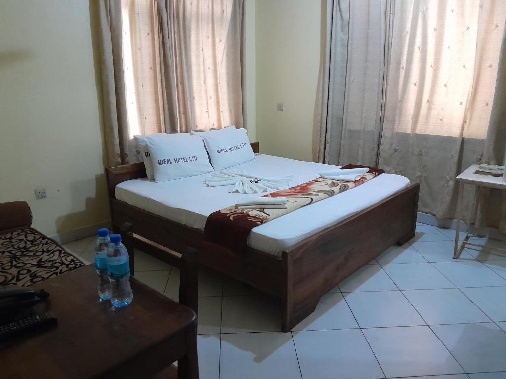 Hotel Ideal في دار السلام: غرفة نوم بسرير وطاولة عليها زجاجتان