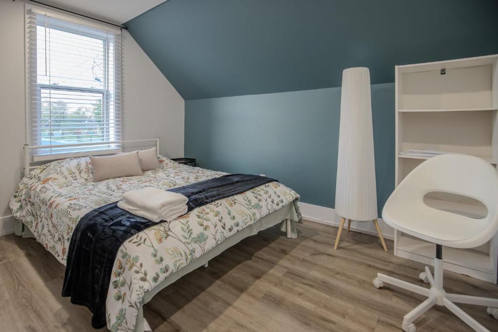 a bedroom with a bed and a white chair at One Bedroom Apartment - 3 Minutes from Downtown in Ottawa