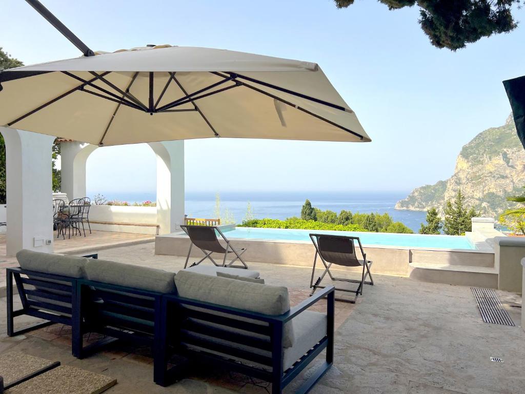 un patio avec une table, des chaises et un parasol dans l'établissement Villa Hibiscus, à Capri