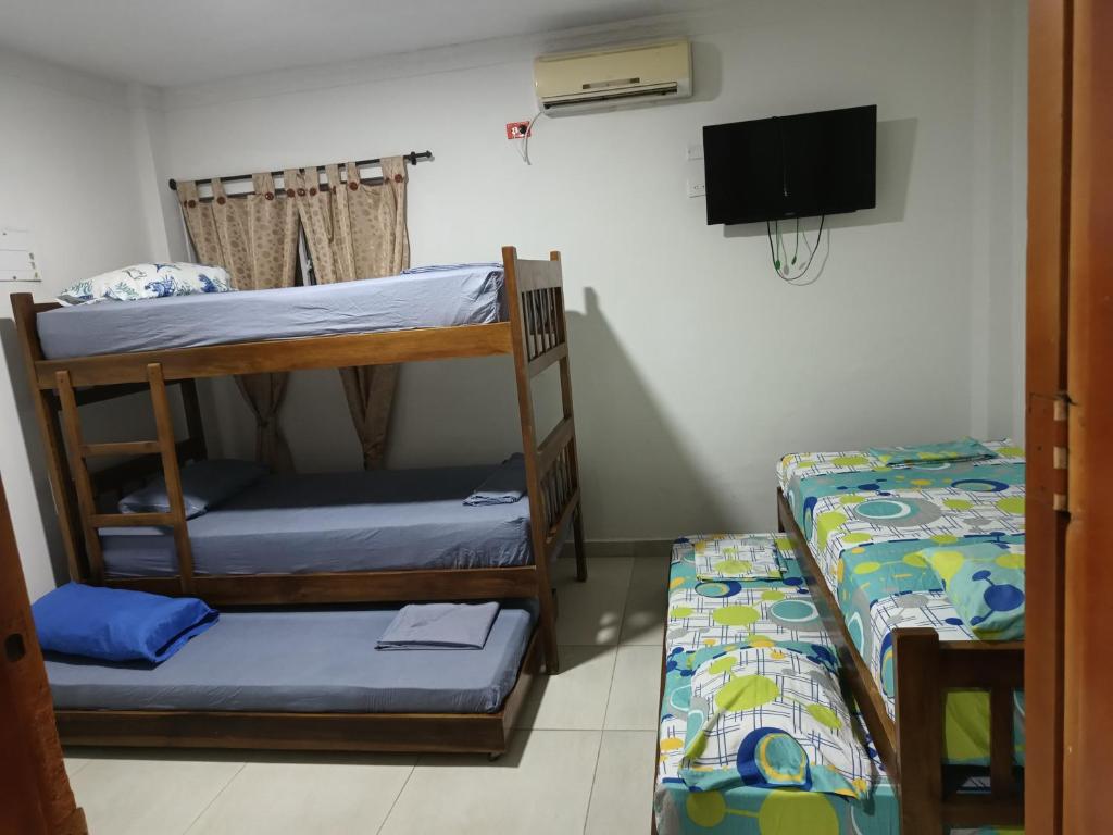 a room with two bunk beds and a flat screen tv at HABITACIONES EN casa de playa in Coveñas