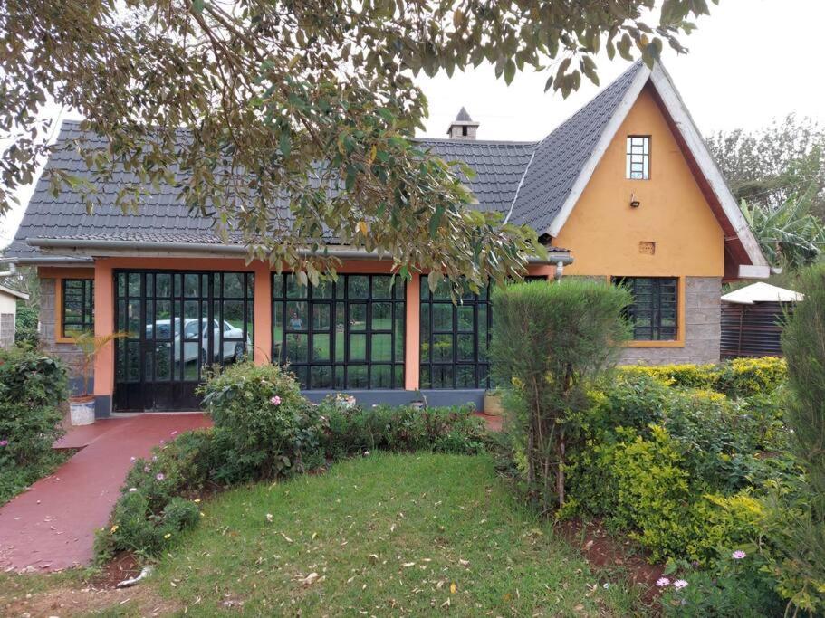 a house with a large windows and a yard at The Orange Cottage in Nyeri
