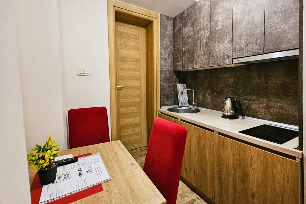 a kitchen with a wooden table and red chairs at Villa Montemaris Budva in Budva