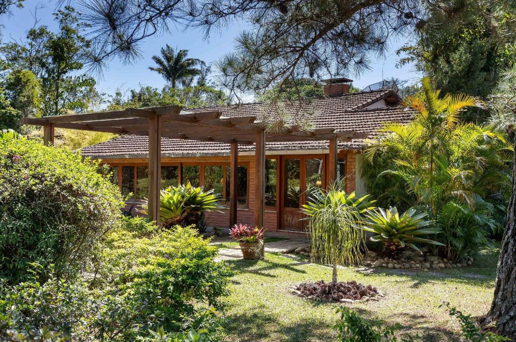 a house with a wooden pergola in a yard at Casa Granja Comary com piscina e jacuzzi privativa in Teresópolis