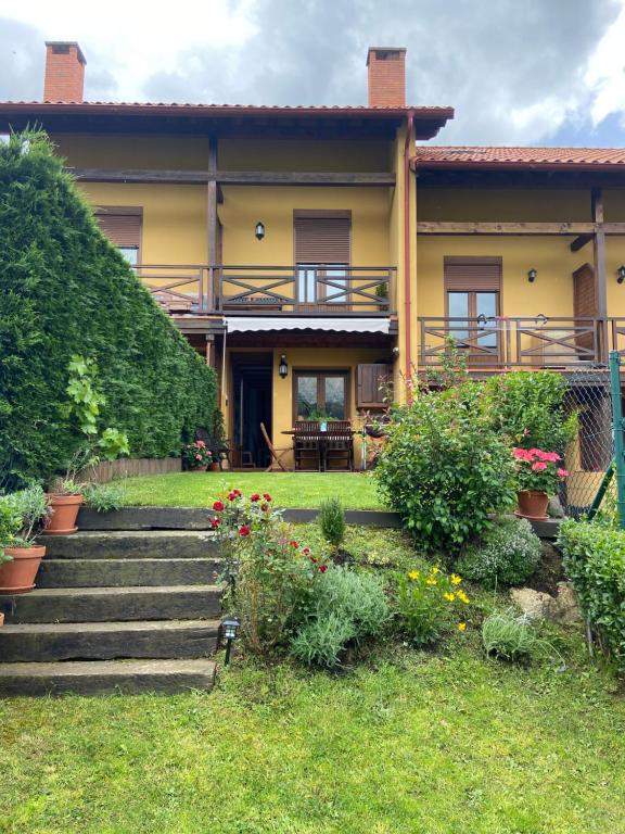 a house with stairs and flowers in the yard at PRECIOSO CHALET JUNTO A POTES CON PISCINA-4 Hab,3 Baños in Ojedo
