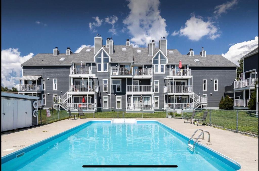 a large house with a swimming pool in front of it at Condo-piscine à 200M du Memphré in Magog-Orford