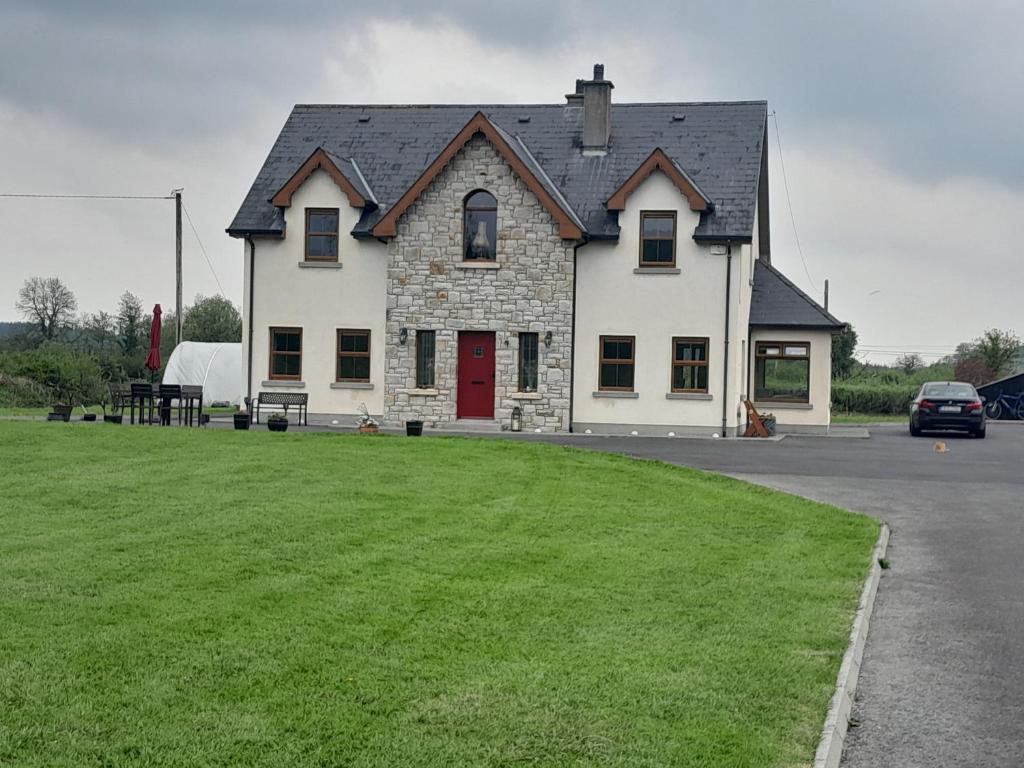 uma grande casa branca com uma porta vermelha e um quintal em Nature's Rest em Carrick on Shannon