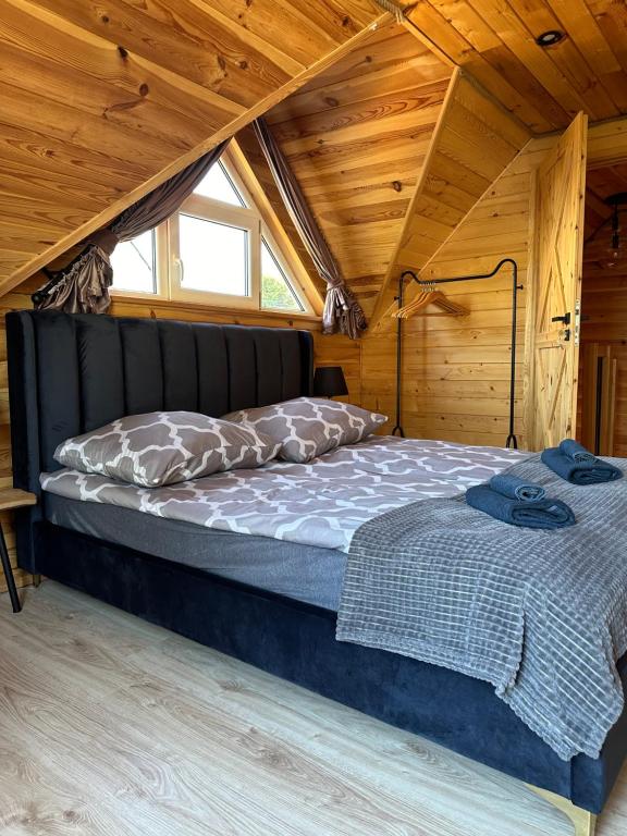 two beds in a room with a wooden ceiling at Na Jeziornej Domki Wypoczynkowe in Żarnowska