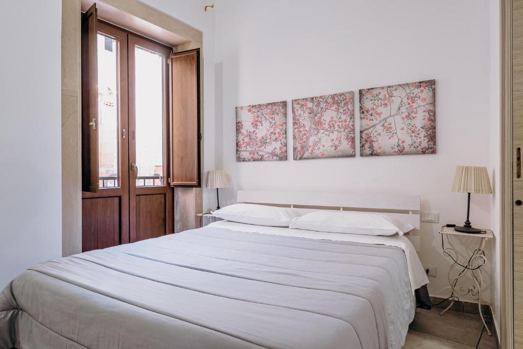 ein weißes Schlafzimmer mit einem großen Bett und einem Fenster in der Unterkunft Siracusa Casa Tiche & Selene in Syrakus