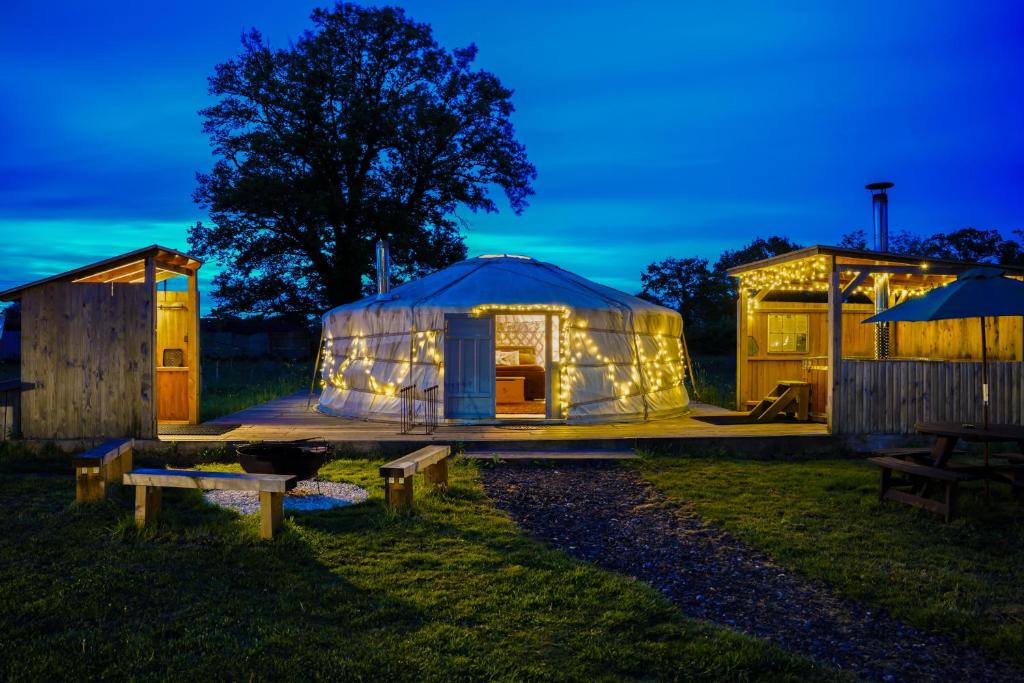 a luxury yurt with lights in a yard at night at Glamp and Tipple Ltd in Great Ellingham