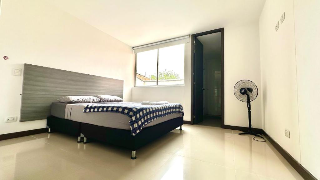 a bedroom with a large bed and a fan at Apartamento moderno en conquistadotes, excelente ubicación. in Medellín