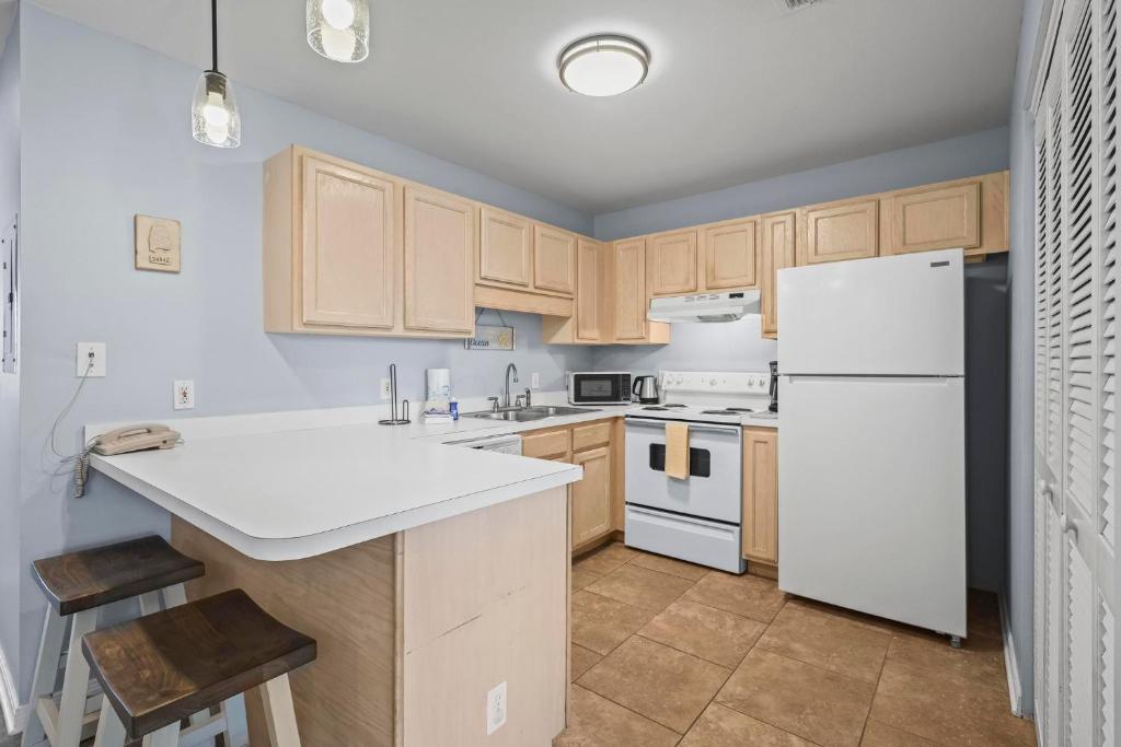 eine Küche mit Holzschränken und einem weißen Kühlschrank in der Unterkunft Condo in Gulf Shores King Suite in Gulf Shores
