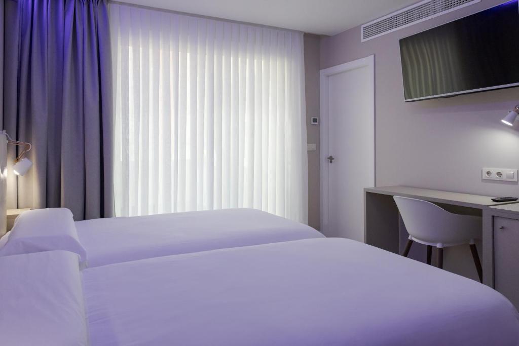 a hotel room with two beds and a desk at Hotel Jucamar in Cangas de Morrazo