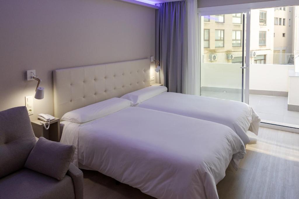 a hotel room with two beds and a window at Hotel Jucamar in Cangas de Morrazo